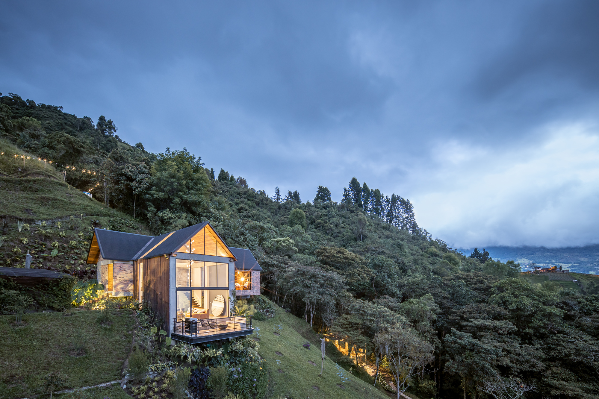Vivienda de autor con fachadas de cristal integrada a una ladera al atardecer